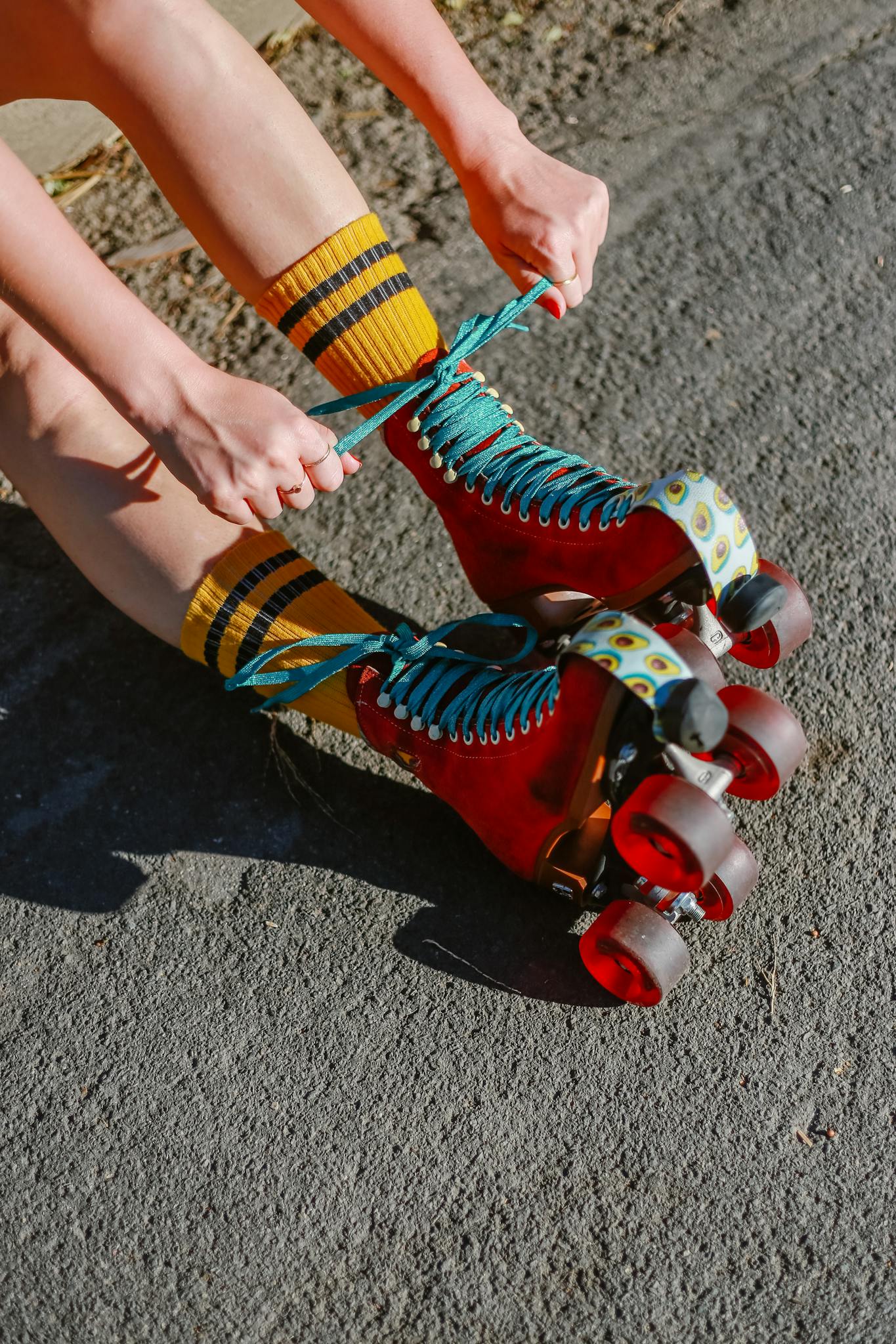Close-up of a person tying red roller skates outdoors, capturing vibrant colors.